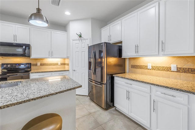 kitchen featuring pendant lighting, white cabinets, light stone countertops, and black appliances