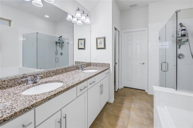 bathroom with a shower with door, vanity, and tile patterned floors