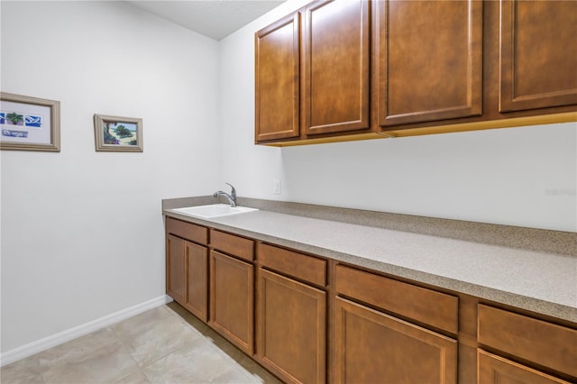 laundry room featuring sink and light tile patterned floors