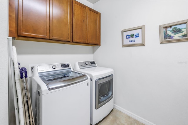 clothes washing area featuring light tile patterned flooring, cabinets, and washer and dryer