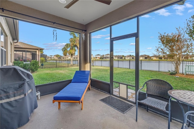 sunroom featuring a water view and ceiling fan