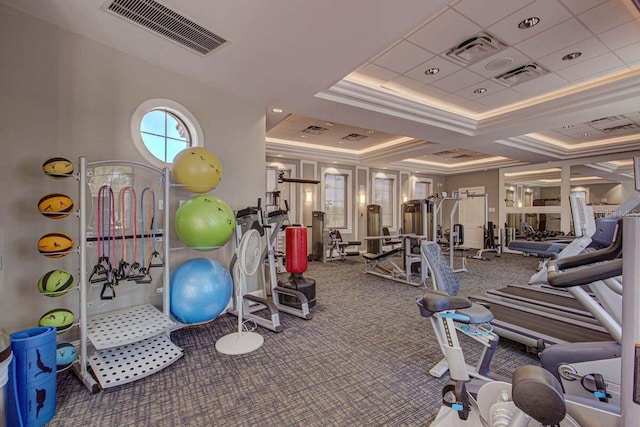 workout area with crown molding, a tray ceiling, and carpet