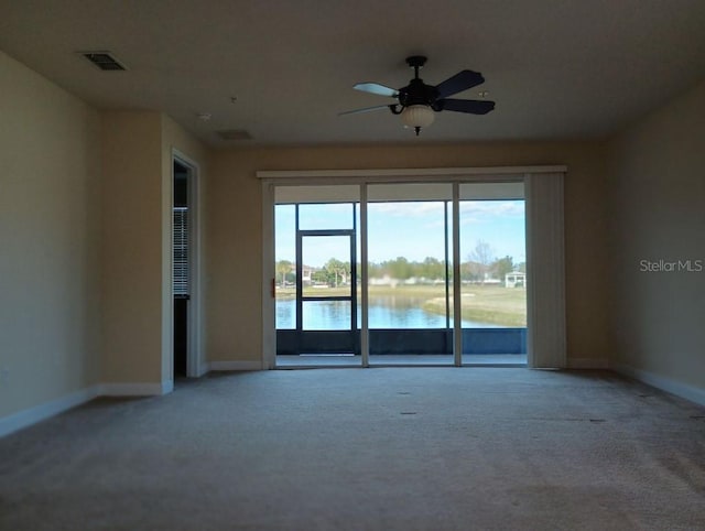 carpeted spare room with ceiling fan and a water view