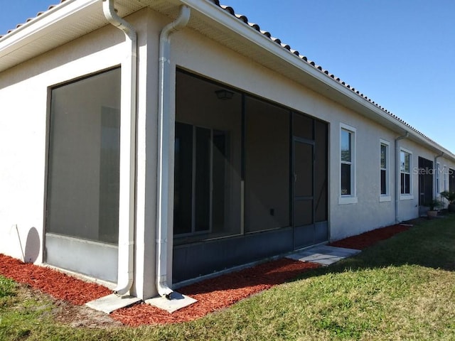 view of home's exterior featuring a yard and a sunroom