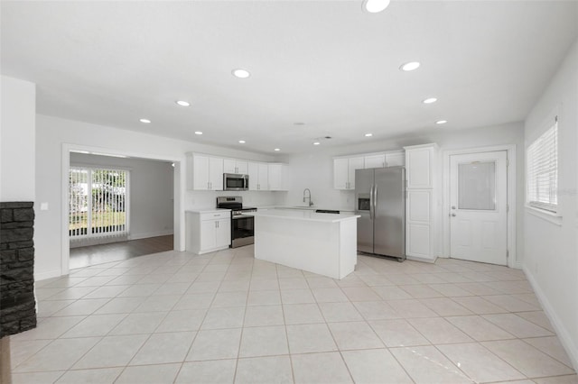 kitchen featuring sink, light tile patterned floors, appliances with stainless steel finishes, a kitchen island, and white cabinets