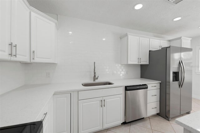 kitchen featuring sink, white cabinets, decorative backsplash, light tile patterned floors, and stainless steel appliances