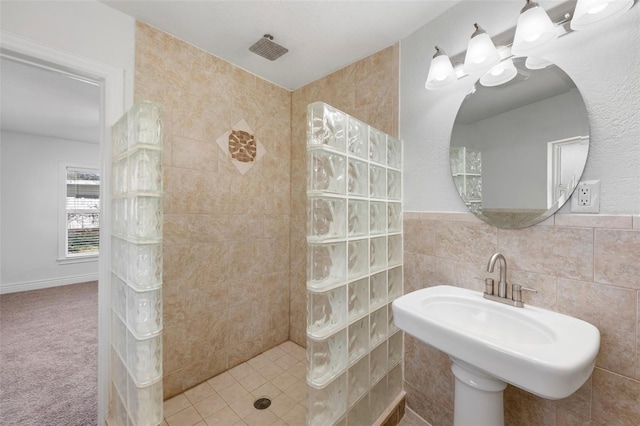 bathroom with sink, tile walls, and a tile shower