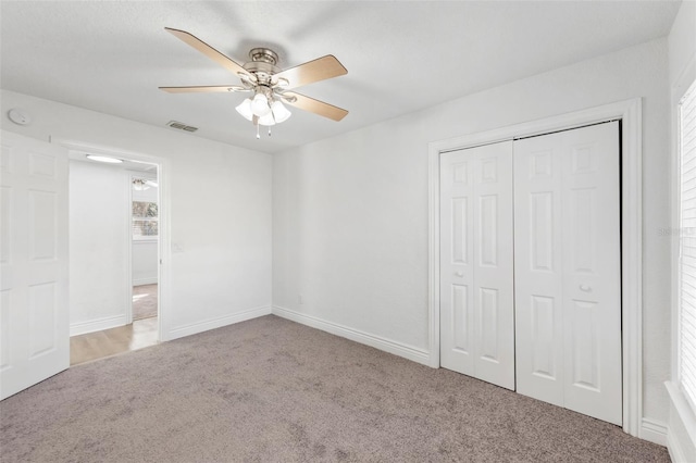 unfurnished bedroom featuring ceiling fan, light colored carpet, and a closet