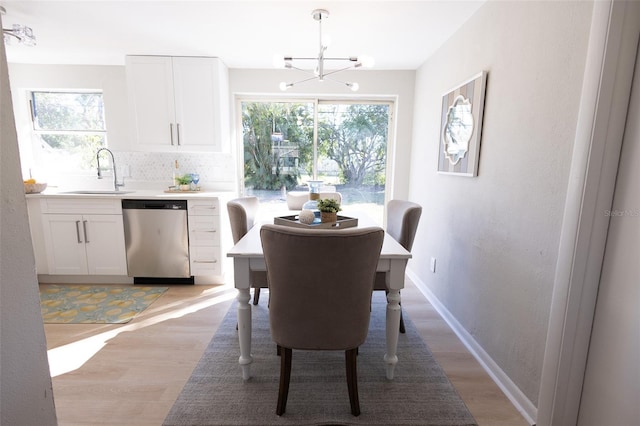 dining room featuring sink, a notable chandelier, and light hardwood / wood-style flooring