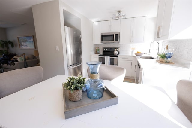 kitchen featuring tasteful backsplash, appliances with stainless steel finishes, sink, and white cabinets