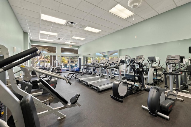 exercise room with a towering ceiling and a paneled ceiling