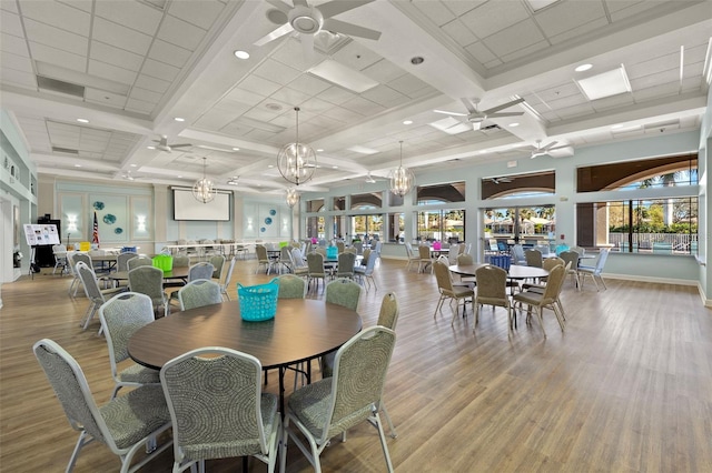 dining space featuring plenty of natural light, coffered ceiling, ceiling fan with notable chandelier, and light hardwood / wood-style flooring