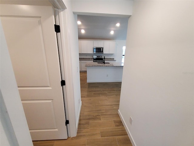 corridor with sink and light wood-type flooring