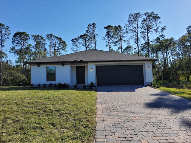 view of front facade featuring a garage, decorative driveway, a front yard, and stucco siding