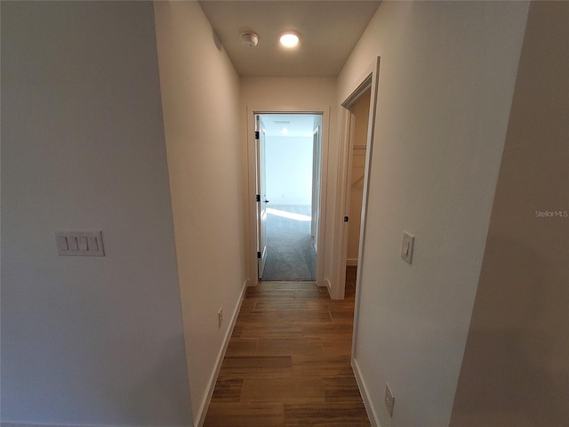 corridor featuring baseboards and dark wood finished floors