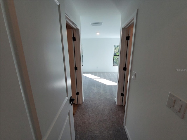 hallway featuring baseboards, visible vents, and carpet flooring