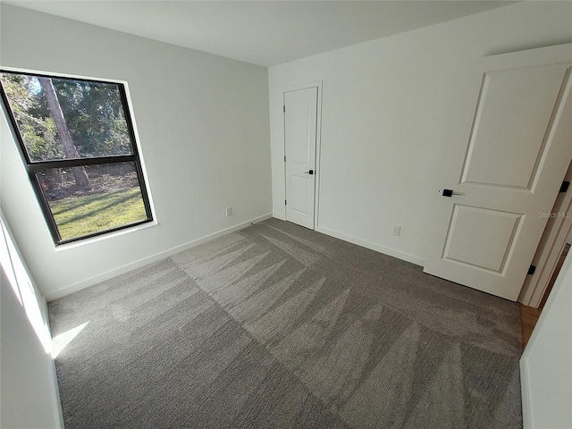 unfurnished bedroom with dark colored carpet and baseboards