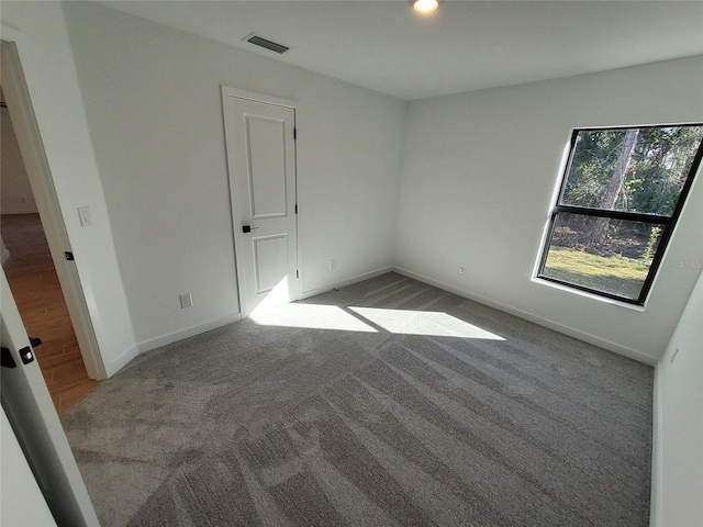 carpeted empty room featuring baseboards, visible vents, and recessed lighting