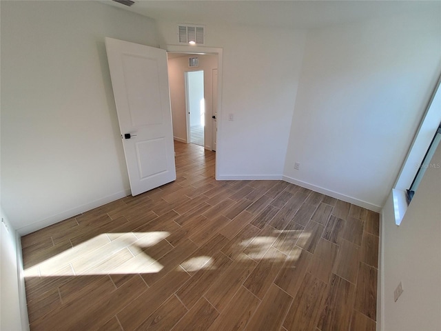 spare room with wood tiled floor, visible vents, and baseboards