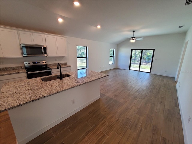 kitchen with appliances with stainless steel finishes, white cabinetry, lofted ceiling, sink, and a kitchen island with sink