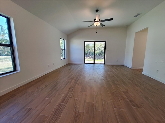 spare room featuring lofted ceiling, wood-type flooring, ceiling fan, and plenty of natural light