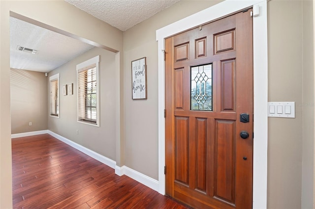 entryway featuring dark wood-type flooring and a textured ceiling