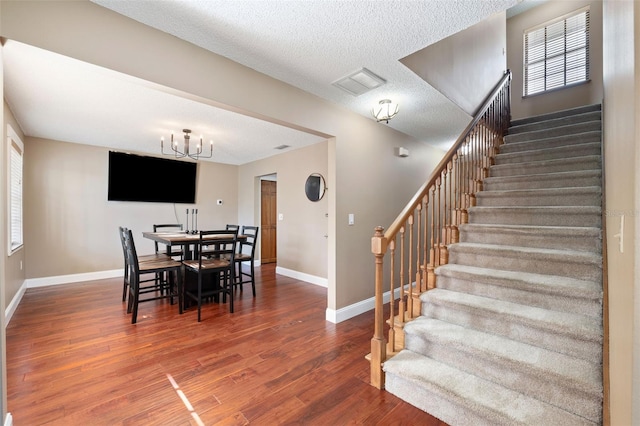 dining space featuring an inviting chandelier, plenty of natural light, dark hardwood / wood-style flooring, and a textured ceiling