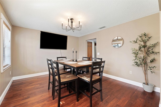 dining space featuring an inviting chandelier, dark hardwood / wood-style flooring, and a textured ceiling