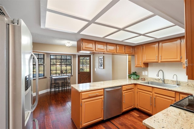 kitchen with stainless steel appliances, sink, dark hardwood / wood-style flooring, and kitchen peninsula