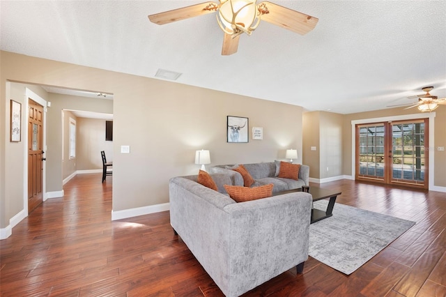 living room with ceiling fan, dark wood-type flooring, and a textured ceiling