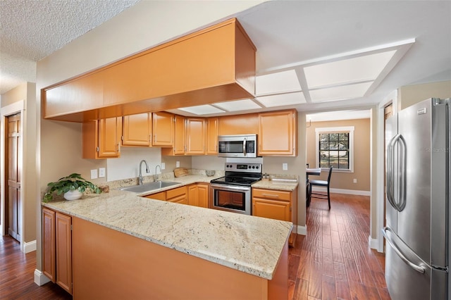 kitchen featuring sink, stainless steel appliances, kitchen peninsula, and light stone countertops