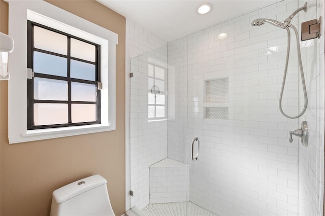 bathroom featuring a shower with door and toilet