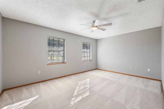 spare room featuring ceiling fan, light carpet, and a textured ceiling