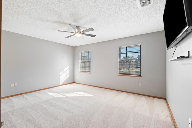 spare room featuring light colored carpet, a textured ceiling, and ceiling fan