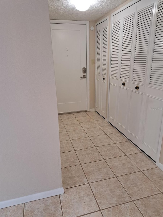 corridor with a textured ceiling and light tile patterned floors