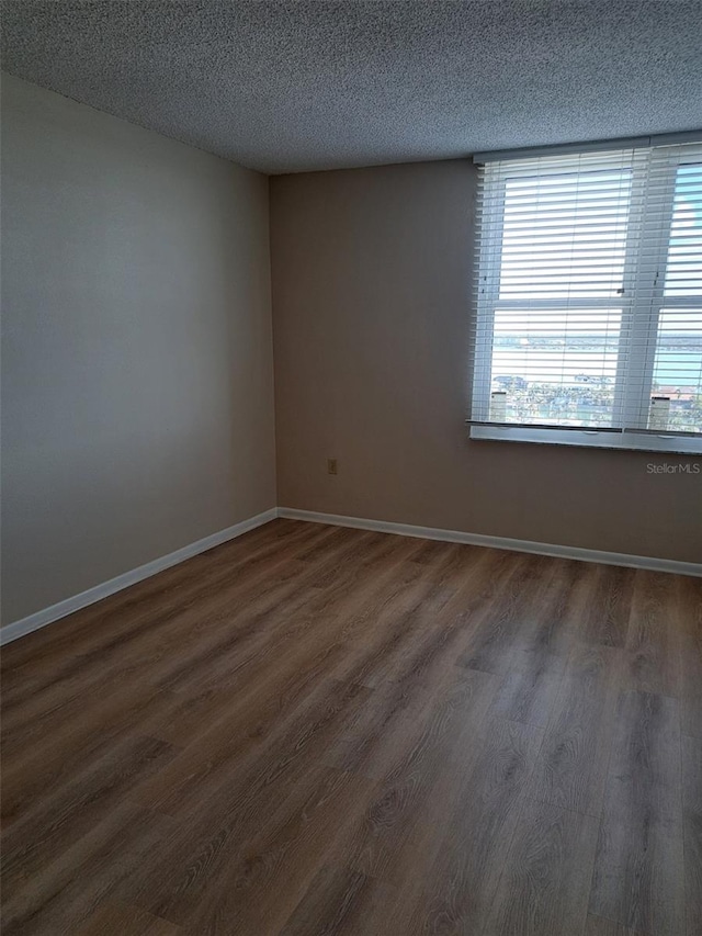 unfurnished room featuring dark wood-type flooring and a textured ceiling