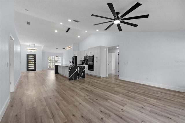 interior space with sink, ceiling fan with notable chandelier, light hardwood / wood-style flooring, and high vaulted ceiling