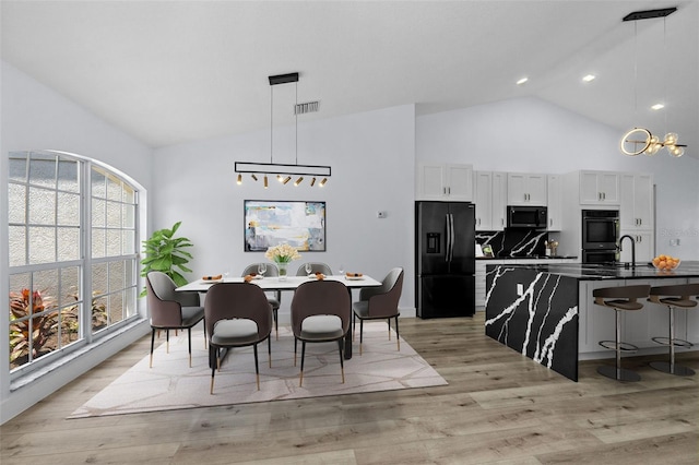 dining space featuring high vaulted ceiling, plenty of natural light, light wood-type flooring, and a notable chandelier