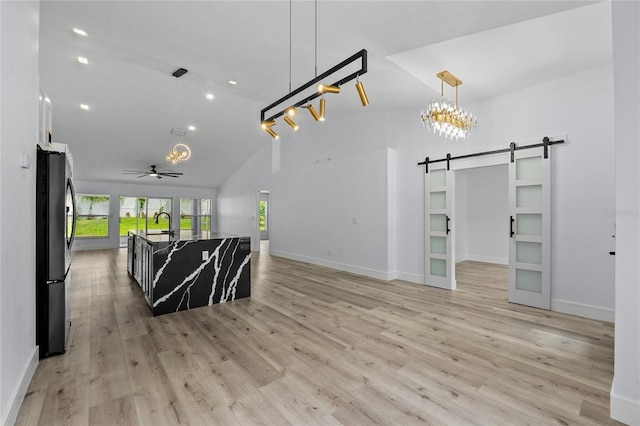 living room featuring sink, light hardwood / wood-style flooring, high vaulted ceiling, and a barn door