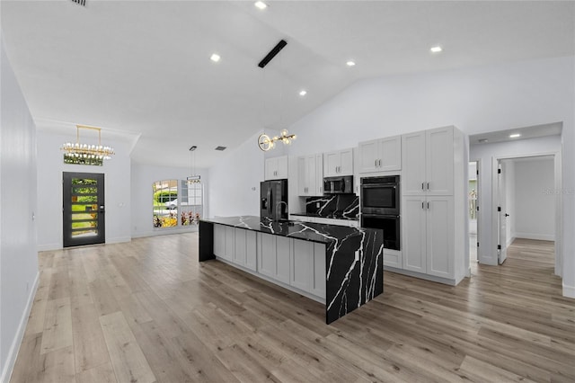 kitchen with white cabinetry, hanging light fixtures, light wood-type flooring, a kitchen island with sink, and black appliances