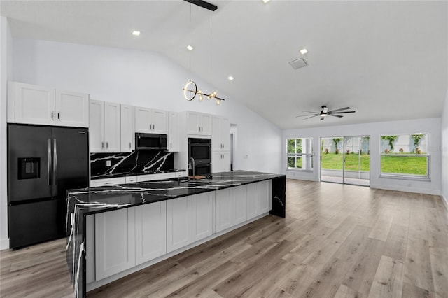 kitchen with tasteful backsplash, black appliances, light hardwood / wood-style floors, white cabinets, and decorative light fixtures