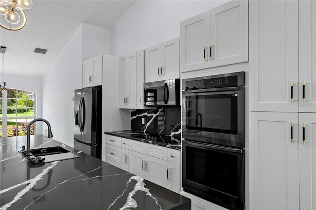 kitchen featuring sink, white cabinetry, double oven, dark stone countertops, and black fridge