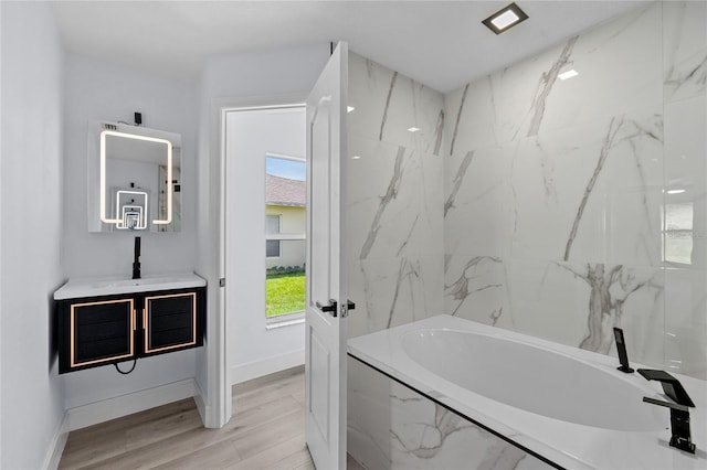 bathroom with vanity, wood-type flooring, and tiled bath