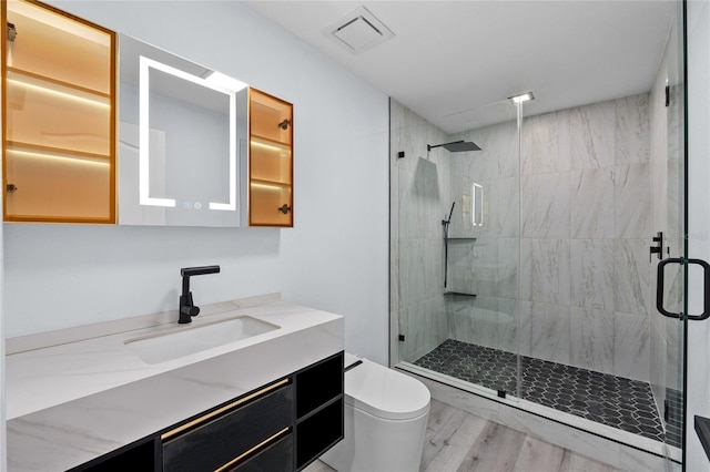 bathroom featuring vanity, hardwood / wood-style flooring, a shower with shower door, and toilet