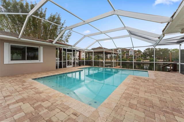 view of pool featuring a patio, a water view, and glass enclosure