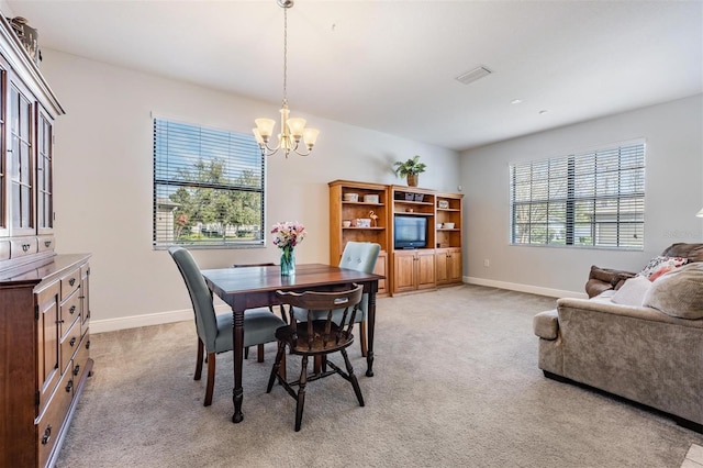 dining area featuring light carpet, a notable chandelier, and baseboards