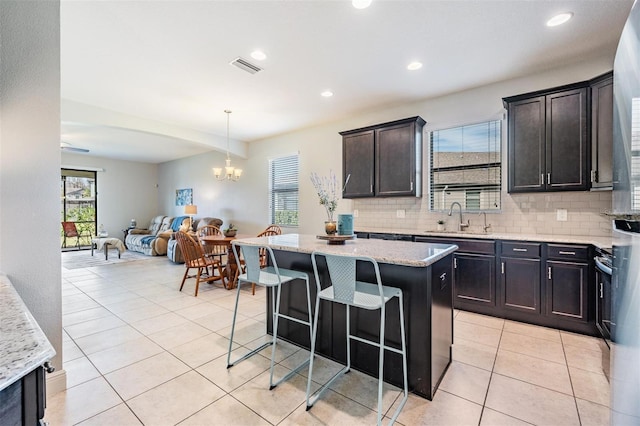 kitchen featuring a kitchen island, sink, light stone counters, and decorative backsplash