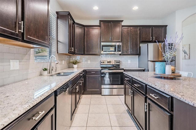 kitchen with sink, dark brown cabinets, light tile patterned floors, stainless steel appliances, and decorative backsplash