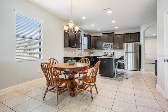 tiled dining area featuring an inviting chandelier and sink