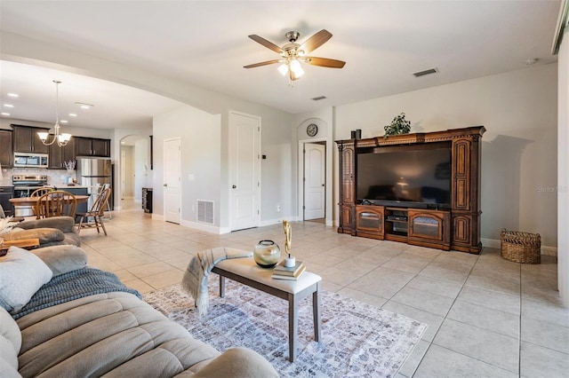 tiled living room featuring ceiling fan with notable chandelier